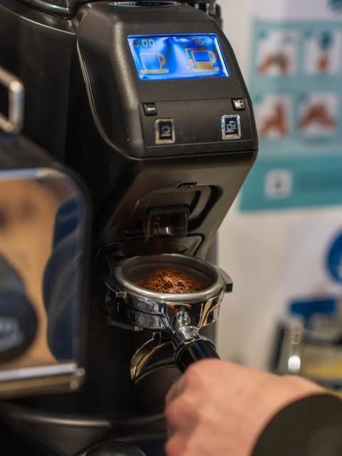 Dosing fresh ground coffee into the portafilter at Kiosk 10